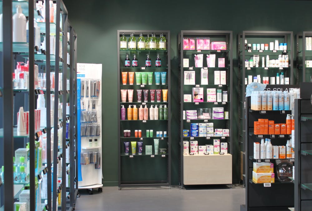 Vue intérieure des étagères de rangement et gondoles dans une pharmacie design rénovée en noir par ArchiPharma